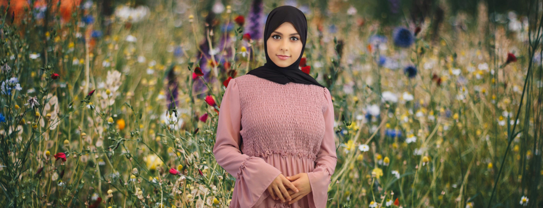 Front View of a Muslim Woman Wearing Pink Smocked Bodice Maxi Dress with a Black Chiffon Hijab